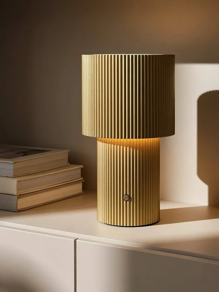 Goldene gerippte Tischlampe, leuchtend, mit einem runden Knopf am Fuß.