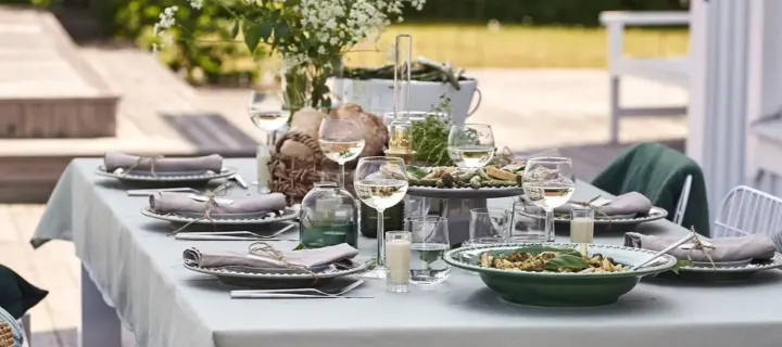 Ein sommerlich gedeckter Tisch mit grünem Thema wird auf der Veranda für eine schöne Gartenparty eingedeckt.