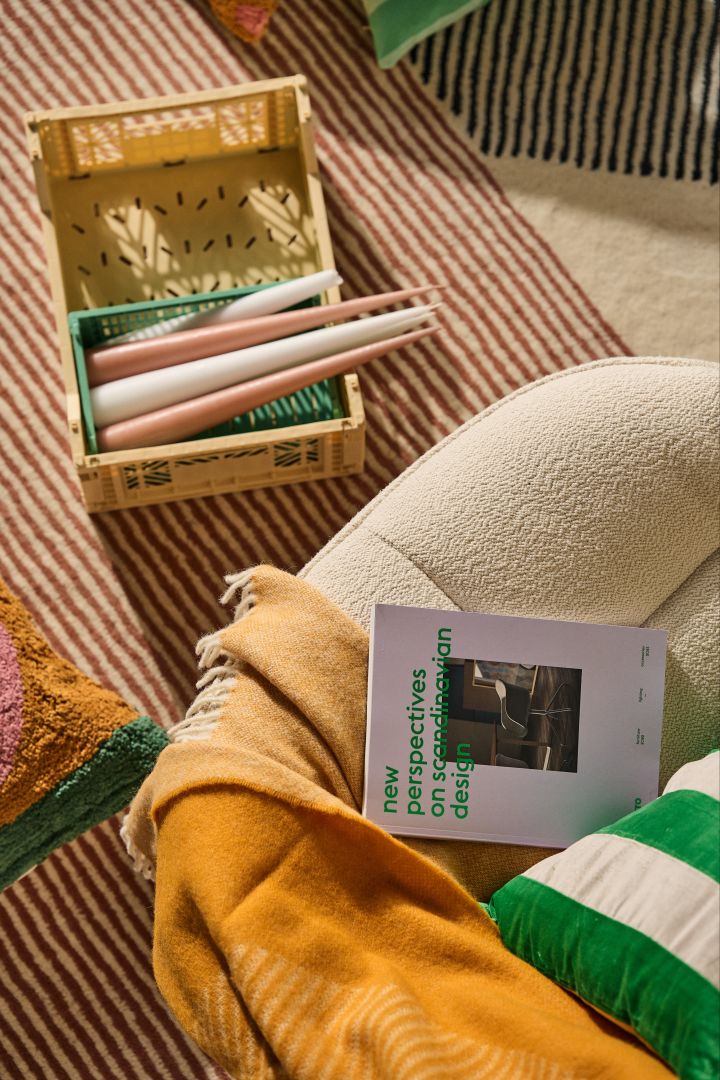 Die Wohntrends für den Herbst 2023 stehen ganz im Zeichen der Farbe: Ein farbenfroher Teppich, eine senffarbene Decke und ein grün gestreiftes Kissen werden in diesem Herbst im Raum zu sehen sein. 