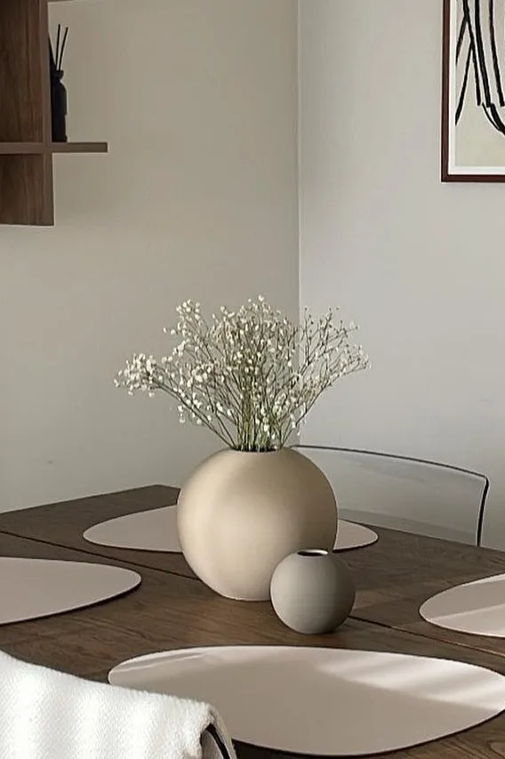Die Ball Vase in Sand und Grau in zwei verschiedenen Größen steht auf einem Esstisch. 