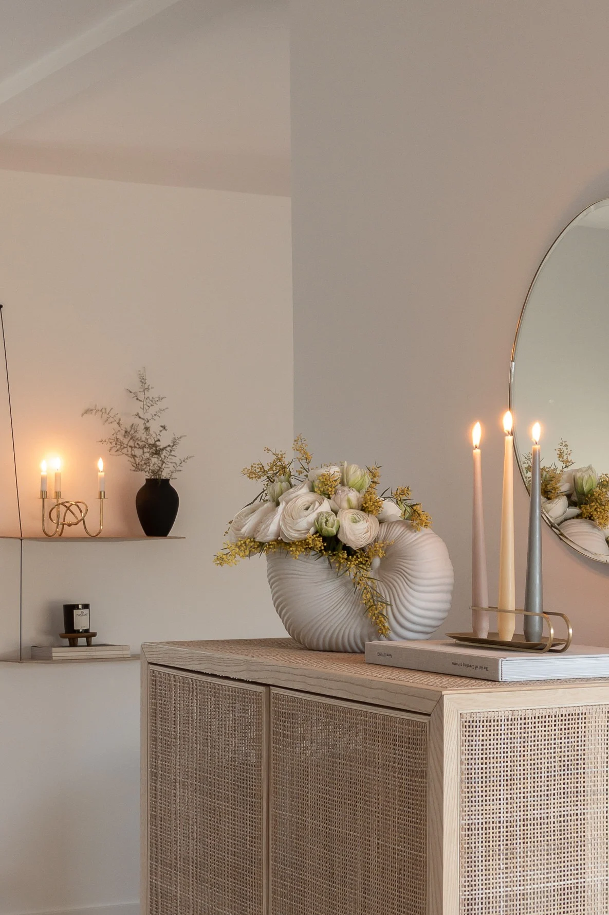 Zur perfekten Lichtplanung gehören auch Kerzen. Hier im Zuhause von @haus_tannenkamp, wo ein Audo Copenhagen Kerzenständer auf einer Kommode steht, daneben die Shell Vase von ferm living mit Blumen und im Hintergrund das Stedge Wandregal von Woud.