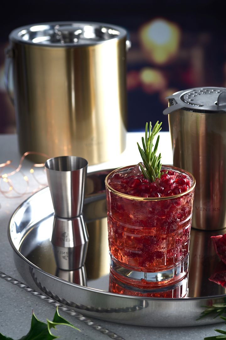 Ein alkoholfreier Cocktail steht auf einem silbernen Tablett, daneben Cocktail-Utensilien wie ein Shaker und der goldene Eiseimer von Viners.