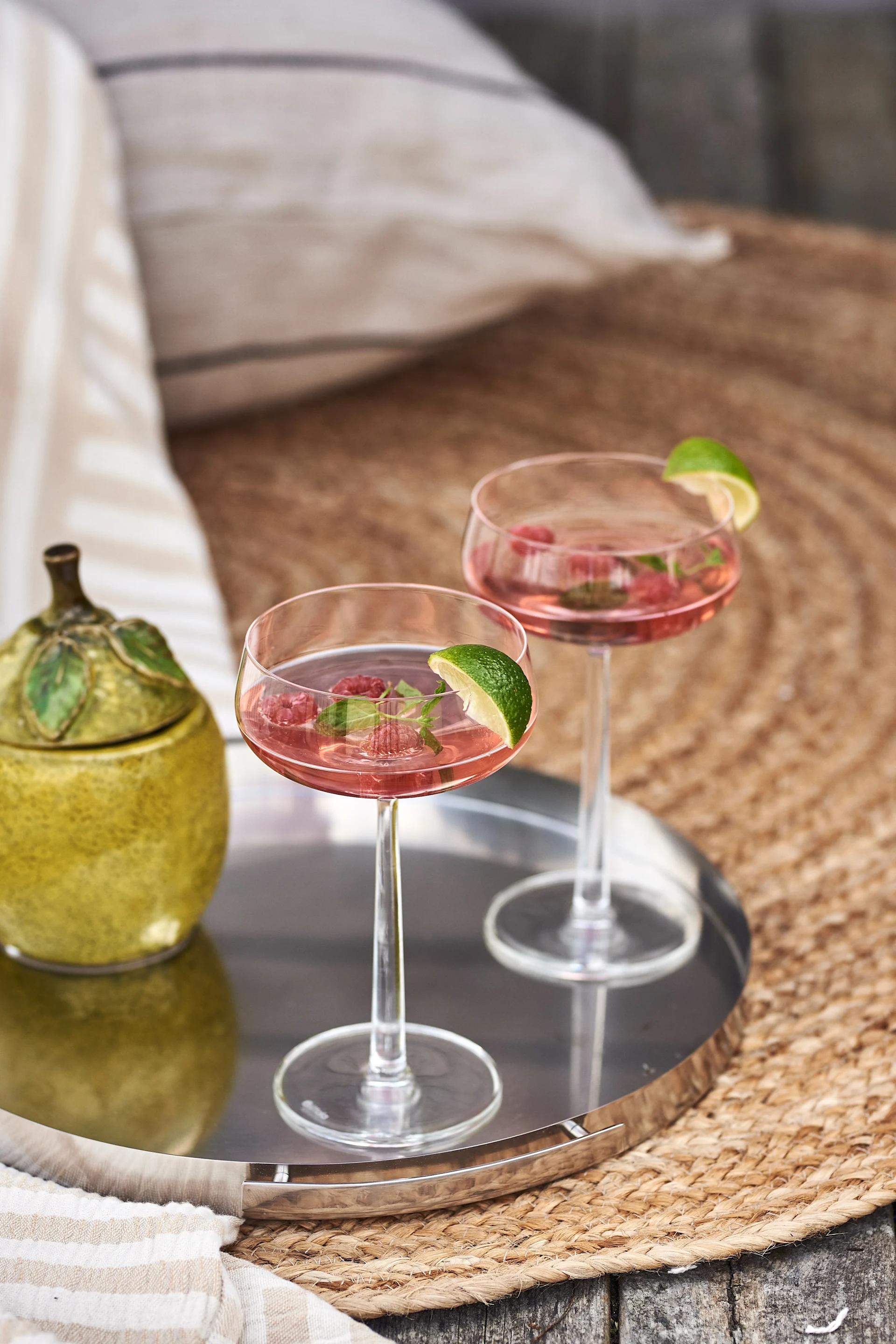 Für einen einfachen und erfrischenden Sommerdrink probieren Sie Gin mit Himbeersaft, garniert mit Zitronenmelisse und frischen Himbeeren, serviert im Essence-Cocktailglas von Iittala.