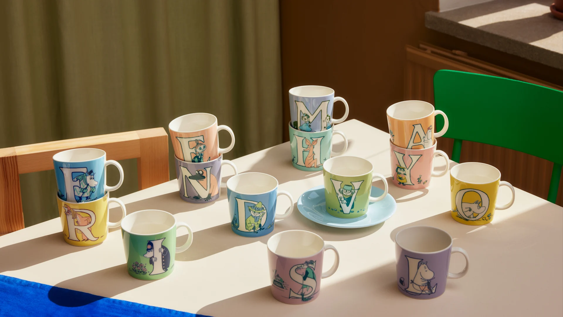 Hier sehen Sie einen großen Teil der Mumin-ABC-Kollektion auf einem Tisch stehen.