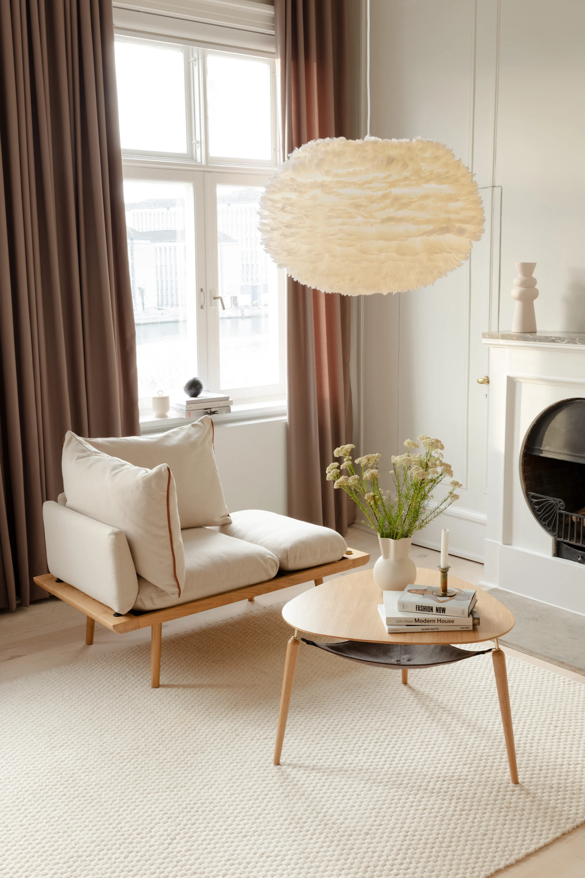 In einem skandinavischen minimalistischen Wohnzimmer hängt die Eos-Deckenleuchte aus Federn von Umage.