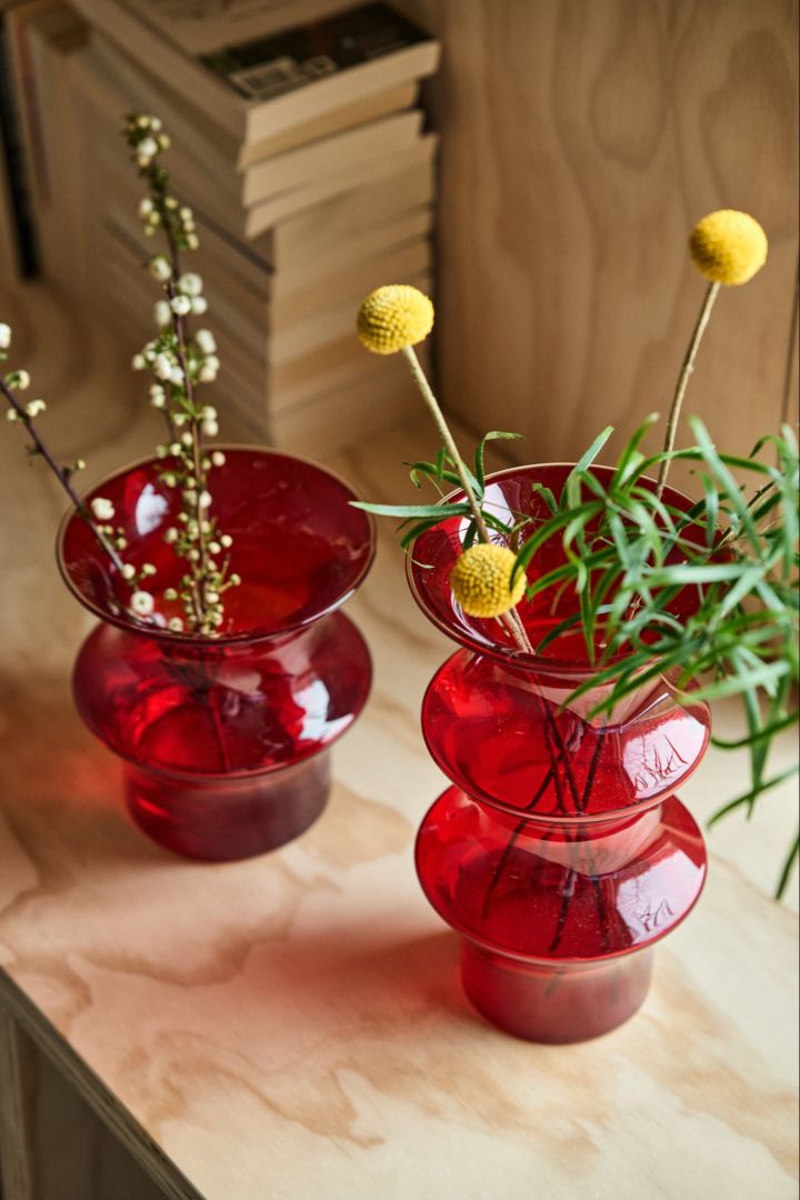 Zwei rote Pagod Vasen stehen nebeneinander auf einer Holzbank.
