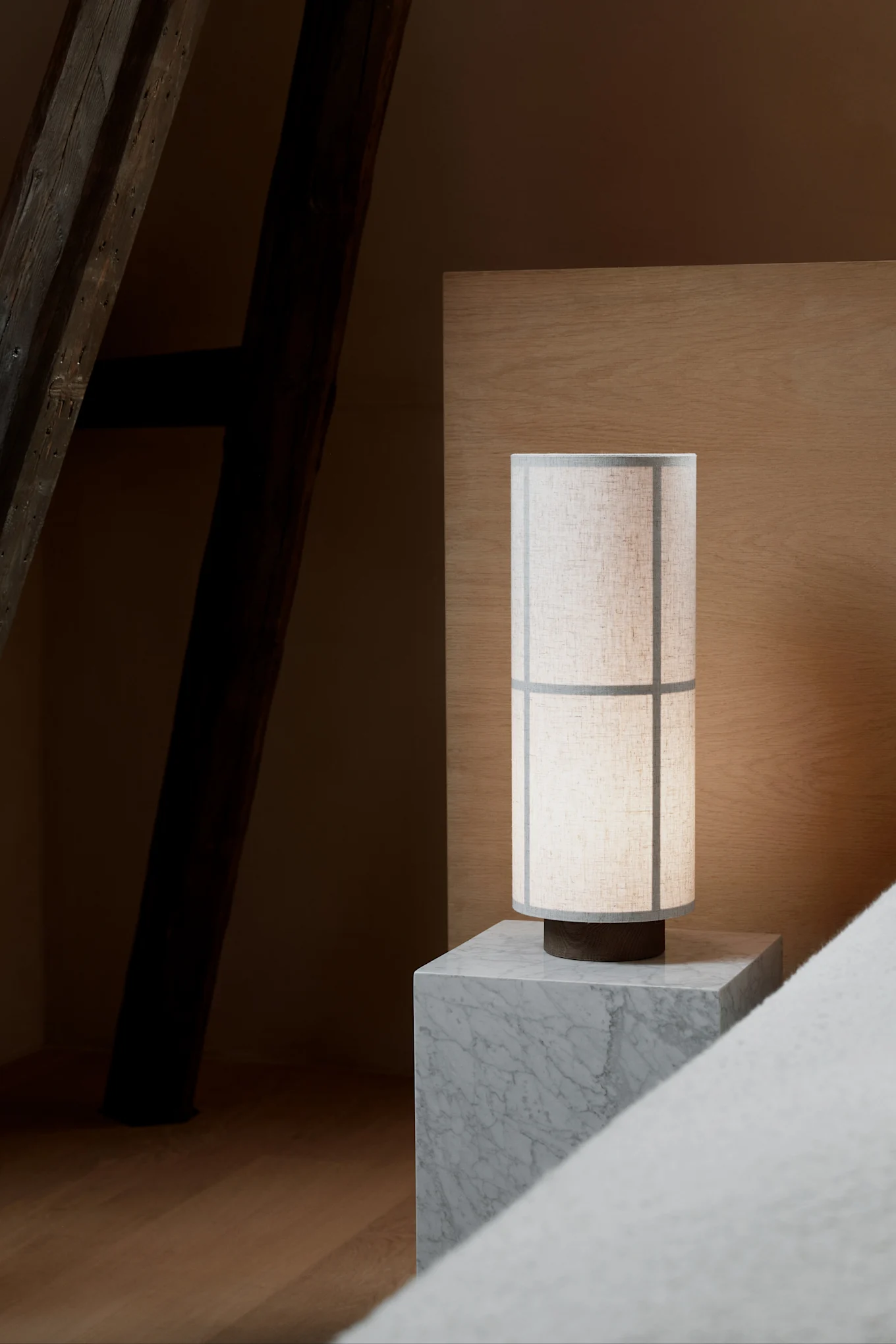 Auf einem grauen marmornen Nachttisch steht die im Japandi-Stil gehaltene Hashira-Tischlampe von Audo Copenhagen.