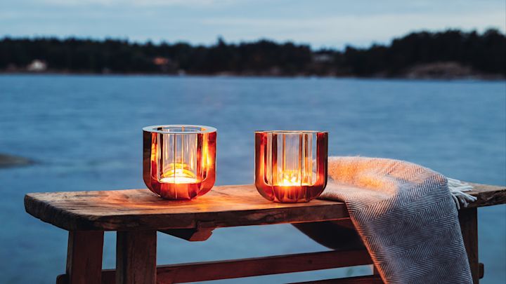 Windlichter outdoor: Zwei Jazz Windlichter von Klong stehen draußen auf einer Bank, im Hintergrund befindet sich ein See.