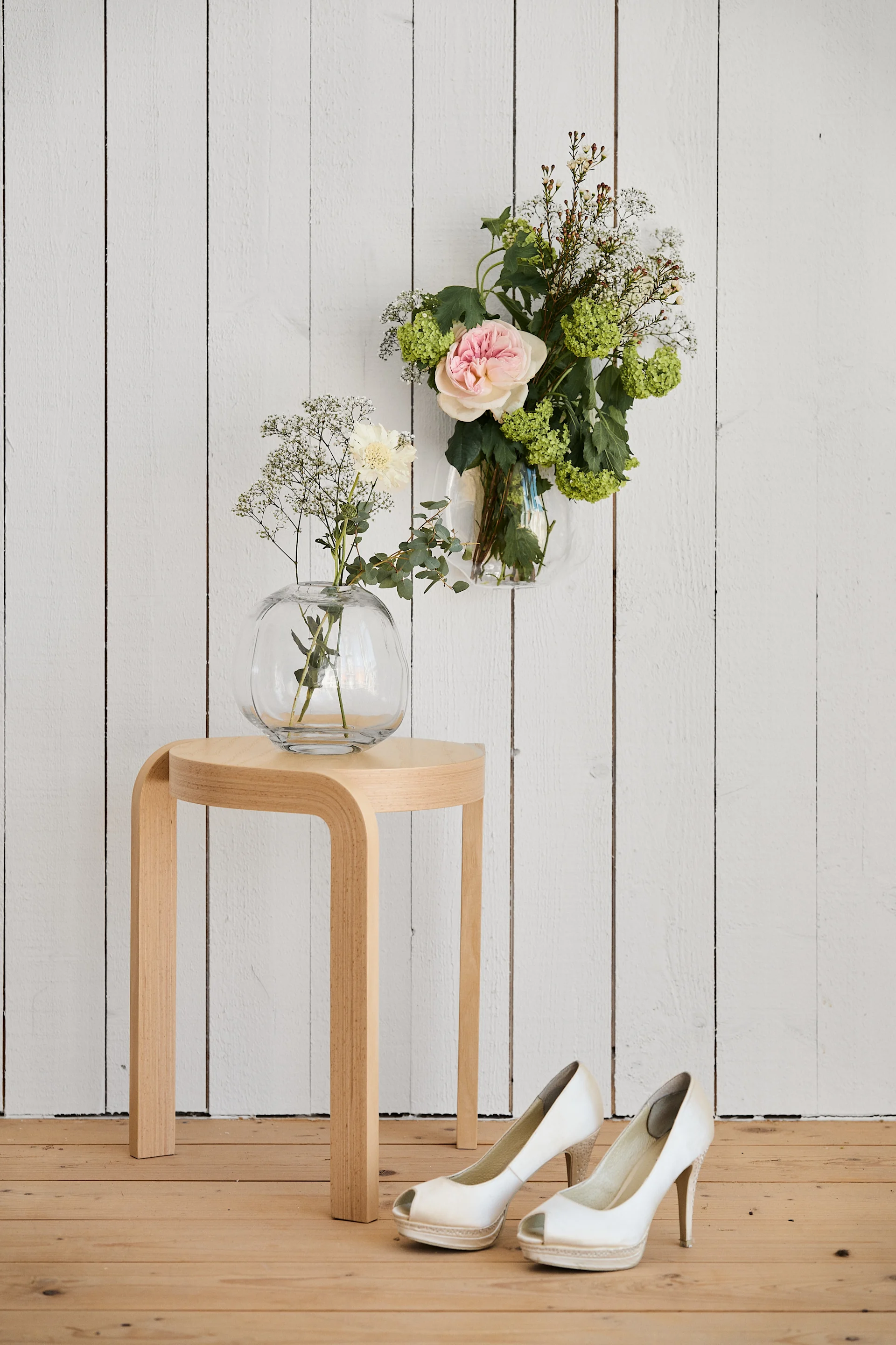 Einzigartige Hochzeitsideen müssen fotografiert werden, um in Erinnerung zu bleiben. Hier sehen Sie einen Holzhocker von Swedese und zwei Vasen, zudem ein Paar Hochzeitsschuhe.
