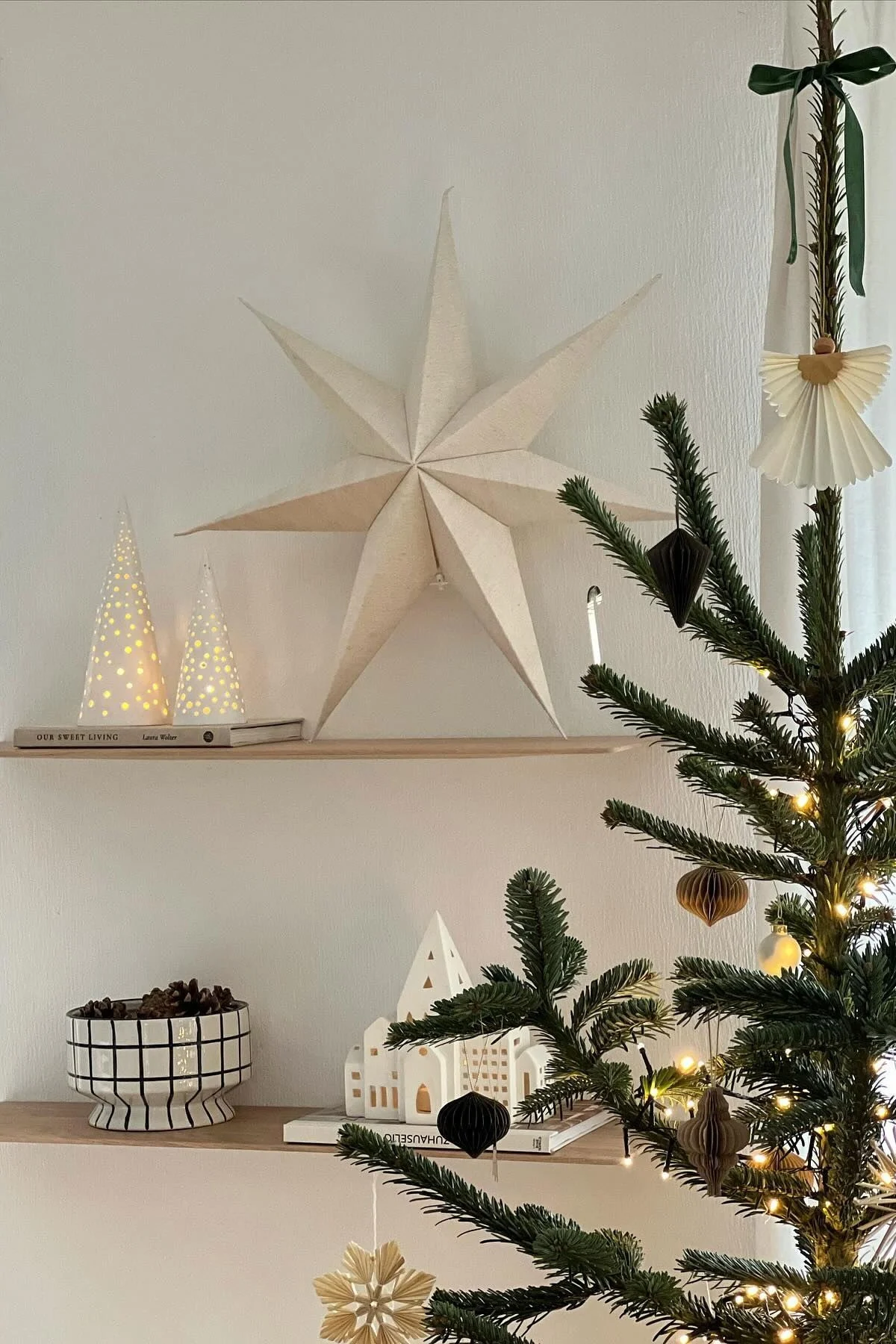 Ein Weihnachtsstern aus Papier von Scandi Living steht zusammen mit mehr Weihnachtsdeko modern auf einem Regal. 