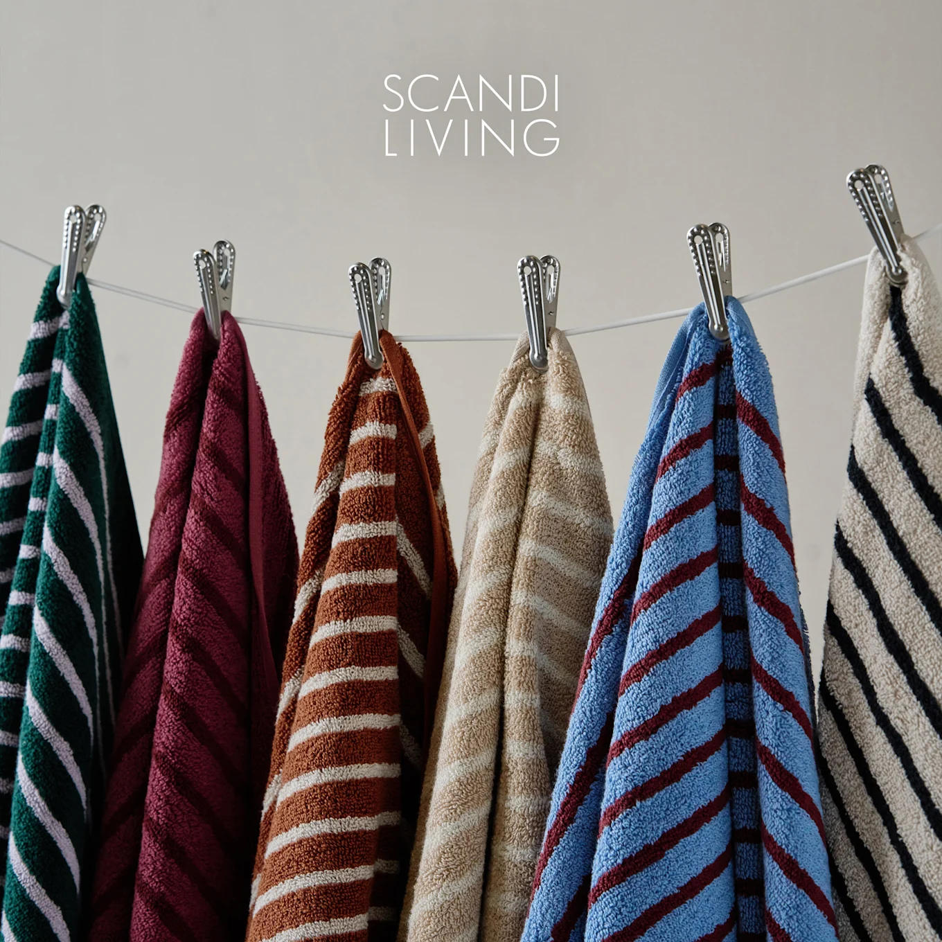 Auswahl gestreifter Handtücher in verschiedenen Farben an einer Wäscheleine, mit Scandi Living Logo.