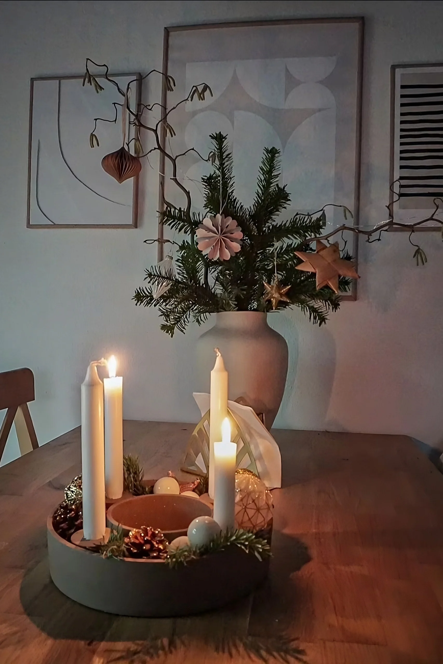 Auf einem Holztisch steht der mit Zapfen und Tannengrün dekorierte The Ring Kerzenhalter von House Doctor.