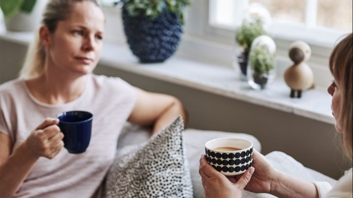 Gemütliches Kaffeetrinken mit der besten Freundin auf dem Sofa, Kaffee aus einer schwarz-weißen Marimekko-Kaffeetasse und einer blauen Rörstrand-Tasse. 