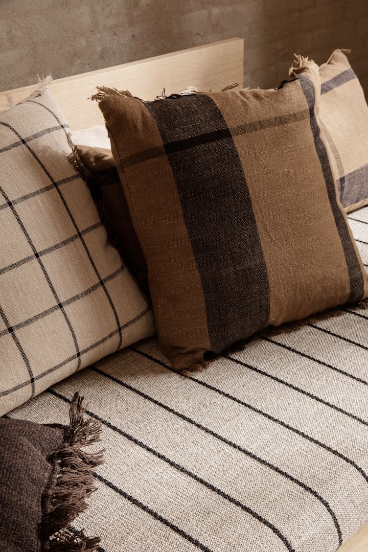 Einer der Herbsttrends 2021 sind karierte Muster. Hier sehen Sie die Calm und Dry Kissen von Ferm Living in herbstlichen Beige- und Brauntönen.