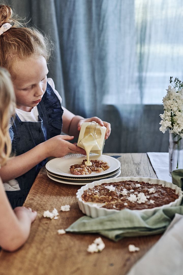 Summer Bucket List: Hier sehen Sie ein Kind, das Vanillesauce auf einen selbst gebackenen Kuchen gießt.