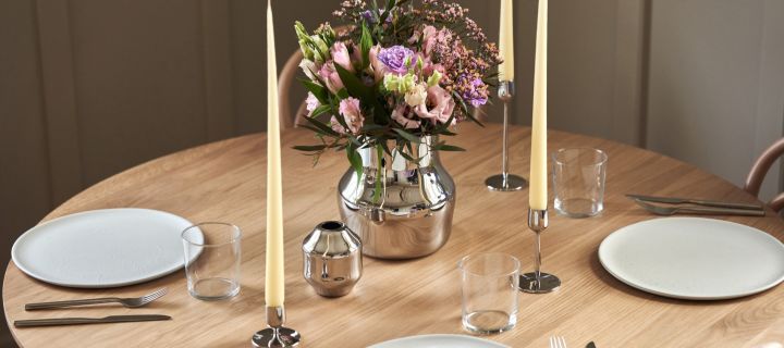 Die neue Kollektion für Gense, entworfen von Monica Förster. Hier sehen Sie die beiden polierten Edelstahlvasen und Kerzenständer auf einem schlicht gedeckten Tisch.
