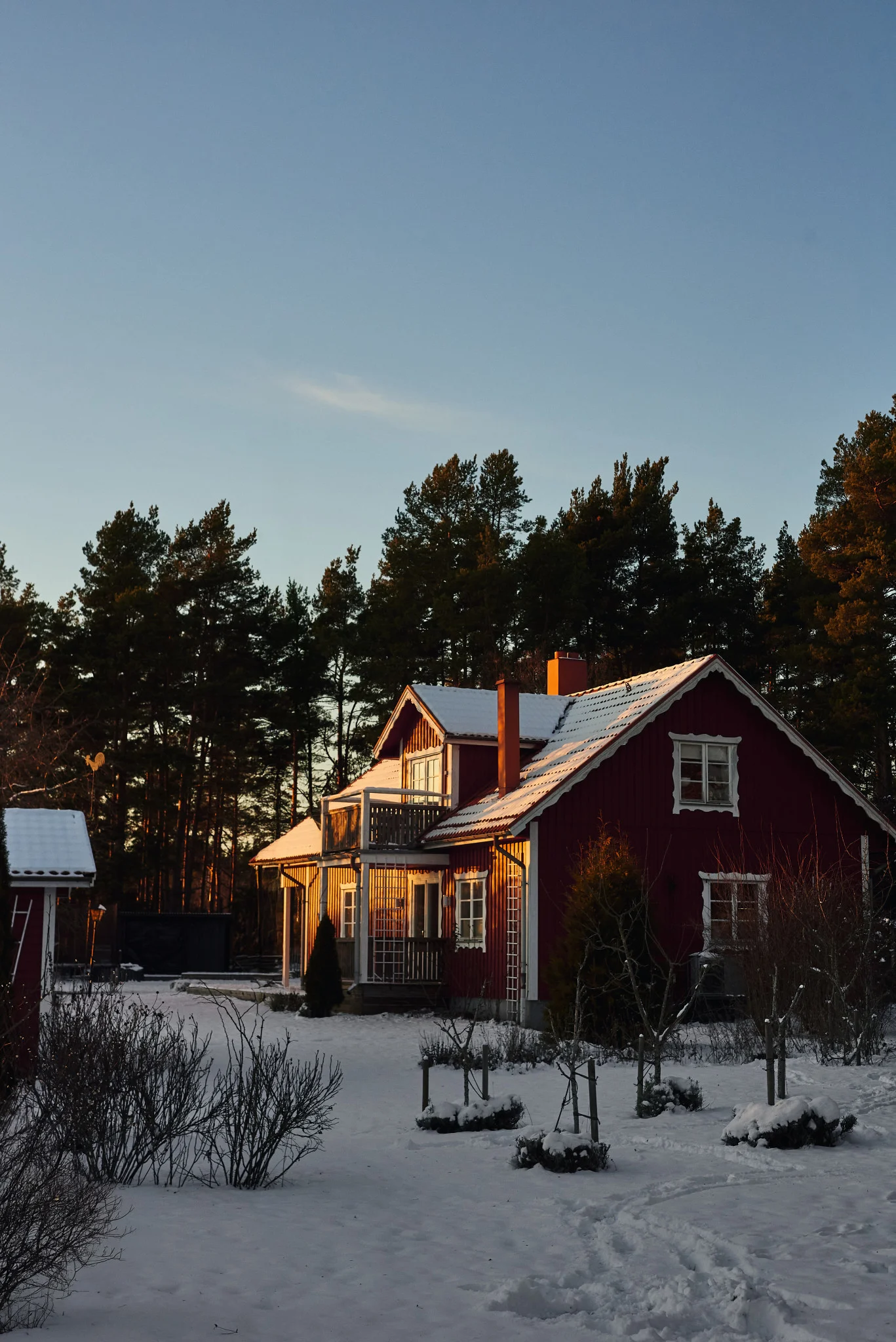 Ein rotes schwedisches Haus in einer verschneiten Landschaft.