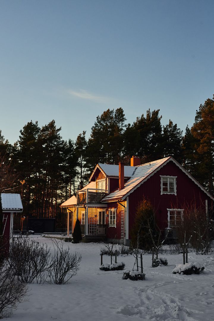 Ein rotes schwedisches Haus in einer verschneiten Landschaft.