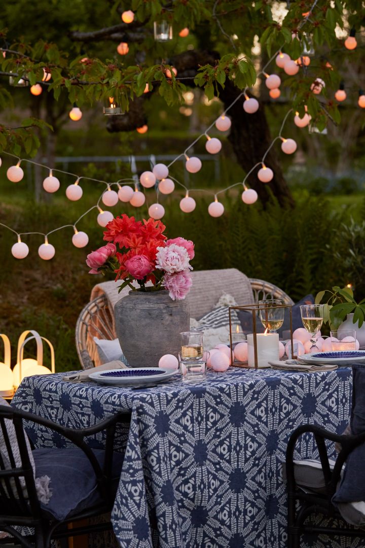 So organisieren Sie ein Grillfest – hier ein sommerlich gedeckter Tisch mit der Rustik Vase von House Doctor und Lichterketten.