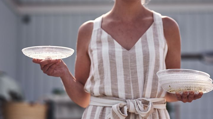 Bei der Gartenparty helfen die Gäste, den Tisch mit den hübschen Kastehelmi-Tellern von Iittala zu decken.