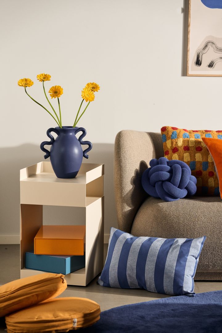 Farbtrends 2024: Die Trendfarben des Jahres sind Blau, Orange und Amber, hier zu sehen in einem farbenfrohen Wohnzimmer mit Kissen und einer Vase.