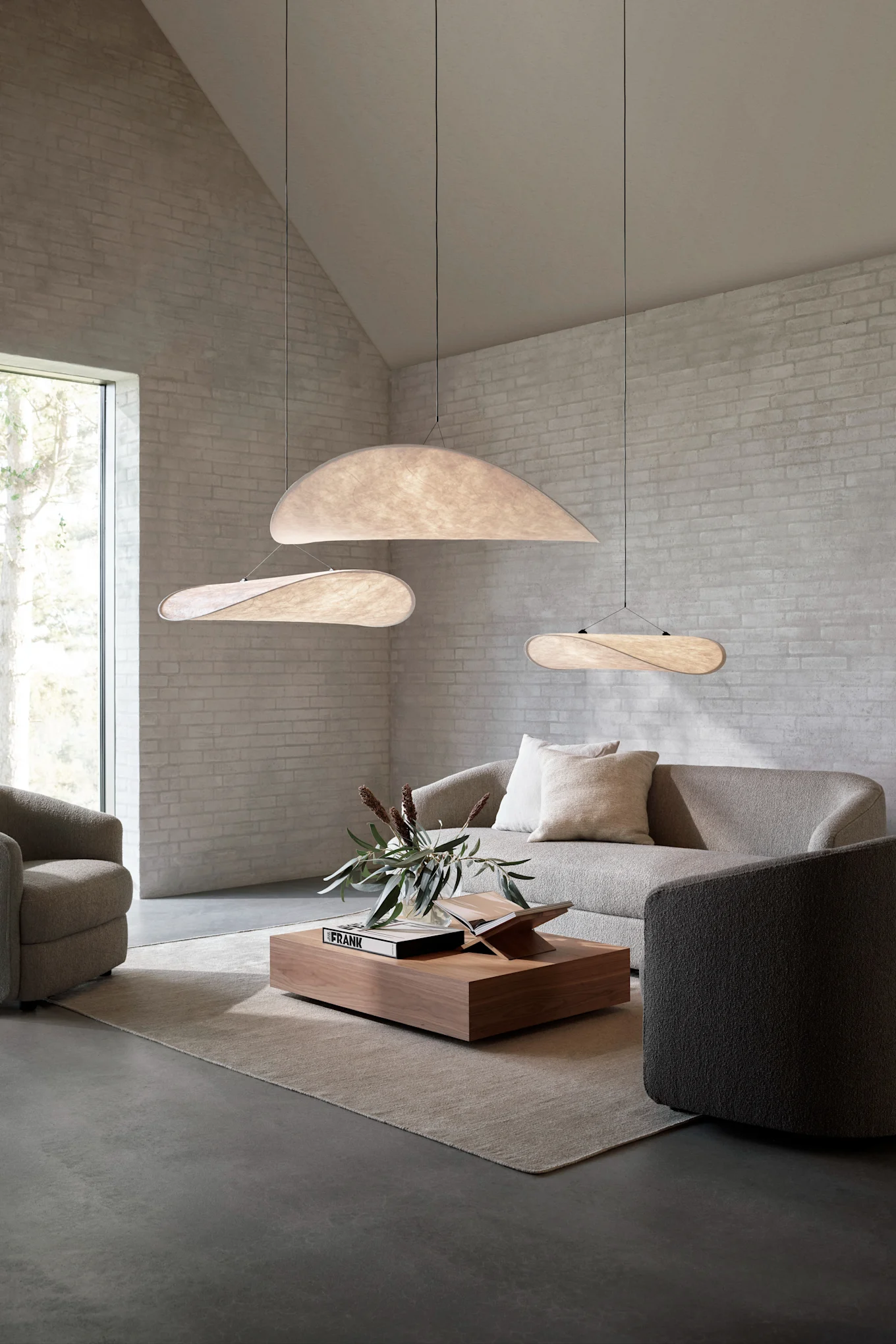 Die richtige Deckenleuchte fürs Wohnzimmer finden: Hier sehen Sie die Tense Pendelleuchte von New Works in verschiedenen Größen in einem Wohnzimmer mit hoher Decke hängen.