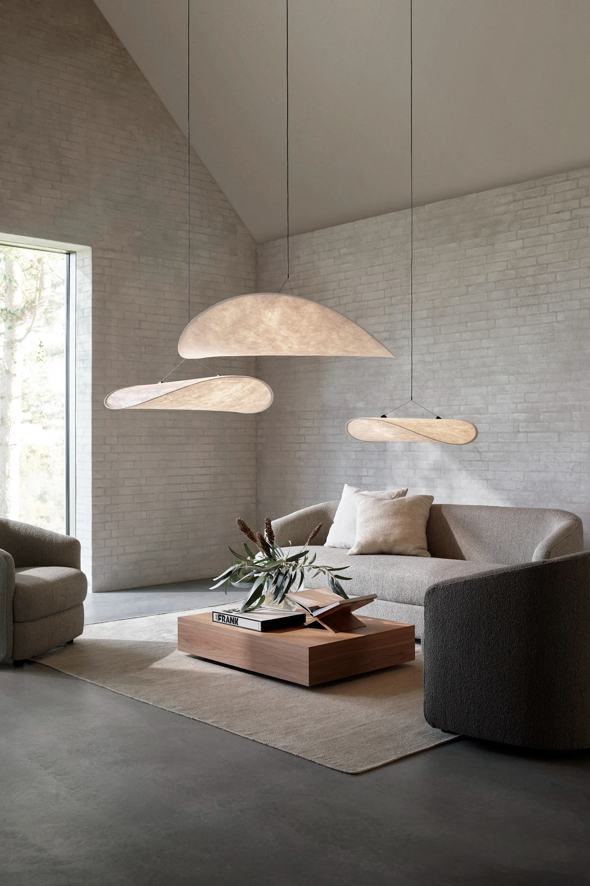 Die richtige Deckenleuchte fürs Wohnzimmer finden: Hier sehen Sie die Tense Pendelleuchte von New Works in verschiedenen Größen in einem Wohnzimmer mit hoher Decke hängen.
