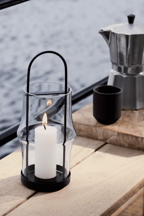 Outdoor Laternen und Windlichter: Hier sehen Sie die Arc Laterne von Holmegaard mit einer Kerze darin draußen stehen.