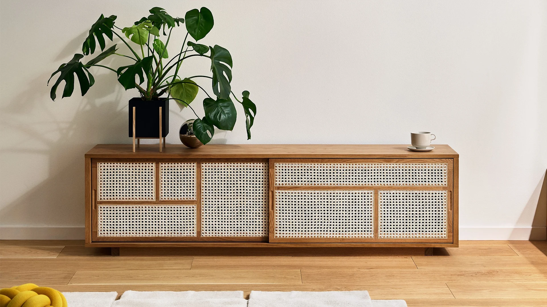 Die Rattan-Elemente des Air Sideboards von Design House Stockholm machen es zur perfekten Boho Deko. Hier wurde es noch mit einer großen Pflanze dekoriert.