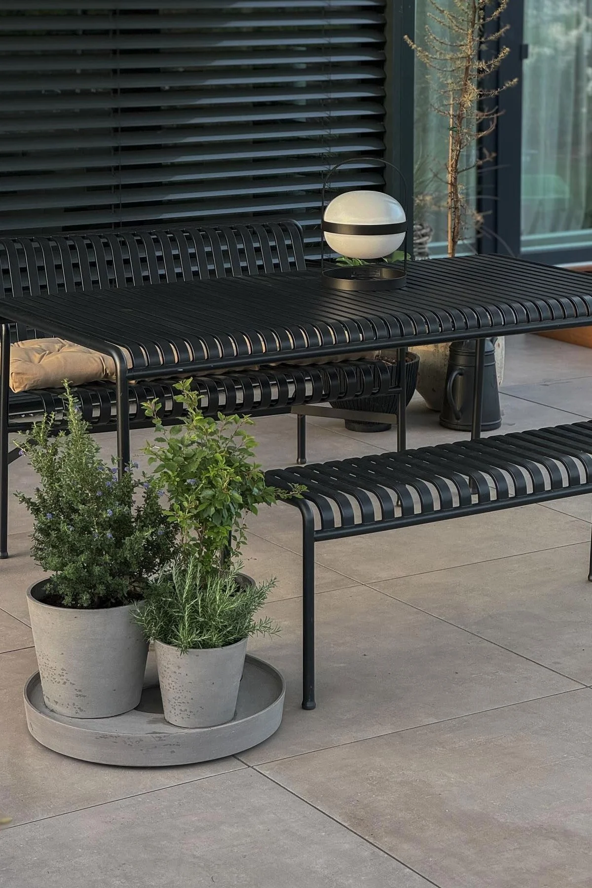 Gartenmöbel aus der Palissade-Kollektion stehen auf der Terrasse von @grauschwarzliebe, davor Blumentöpfe mit Kräutern darin und auf dem Tisch steht eine Soft Spot Solarzellenlampe von Rosendahl.