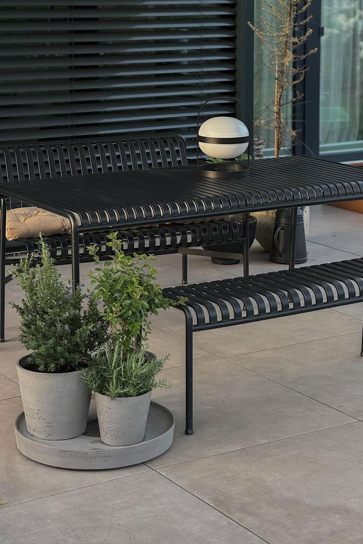 Gartenmöbel aus der Palissade-Kollektion stehen auf der Terrasse von @grauschwarzliebe, davor Blumentöpfe mit Kräutern darin und auf dem Tisch steht eine Soft Spot Solarzellenlampe von Rosendahl.