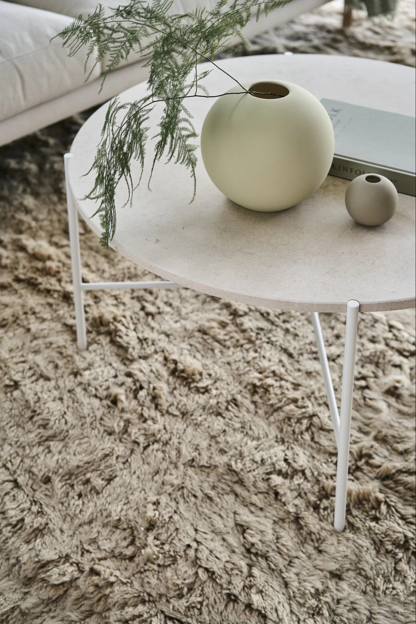 Die ikonische Ball Vase in Shell und Sand von Cooee Design auf einem Beistelltisch in einem skandinavisch eingerichteten Wohnzimmer.