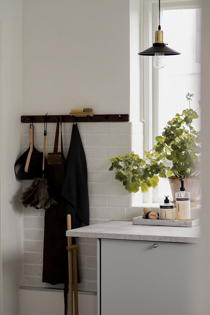 Kleinere Pendelleuchten sorgen für eine punktuelle Beleuchtung der Küche. Hier sehen Sie die Disc Mini Pendelleuchte in Schwarz von Globen Lighting in einer Küche vor einem Fenster hängen.