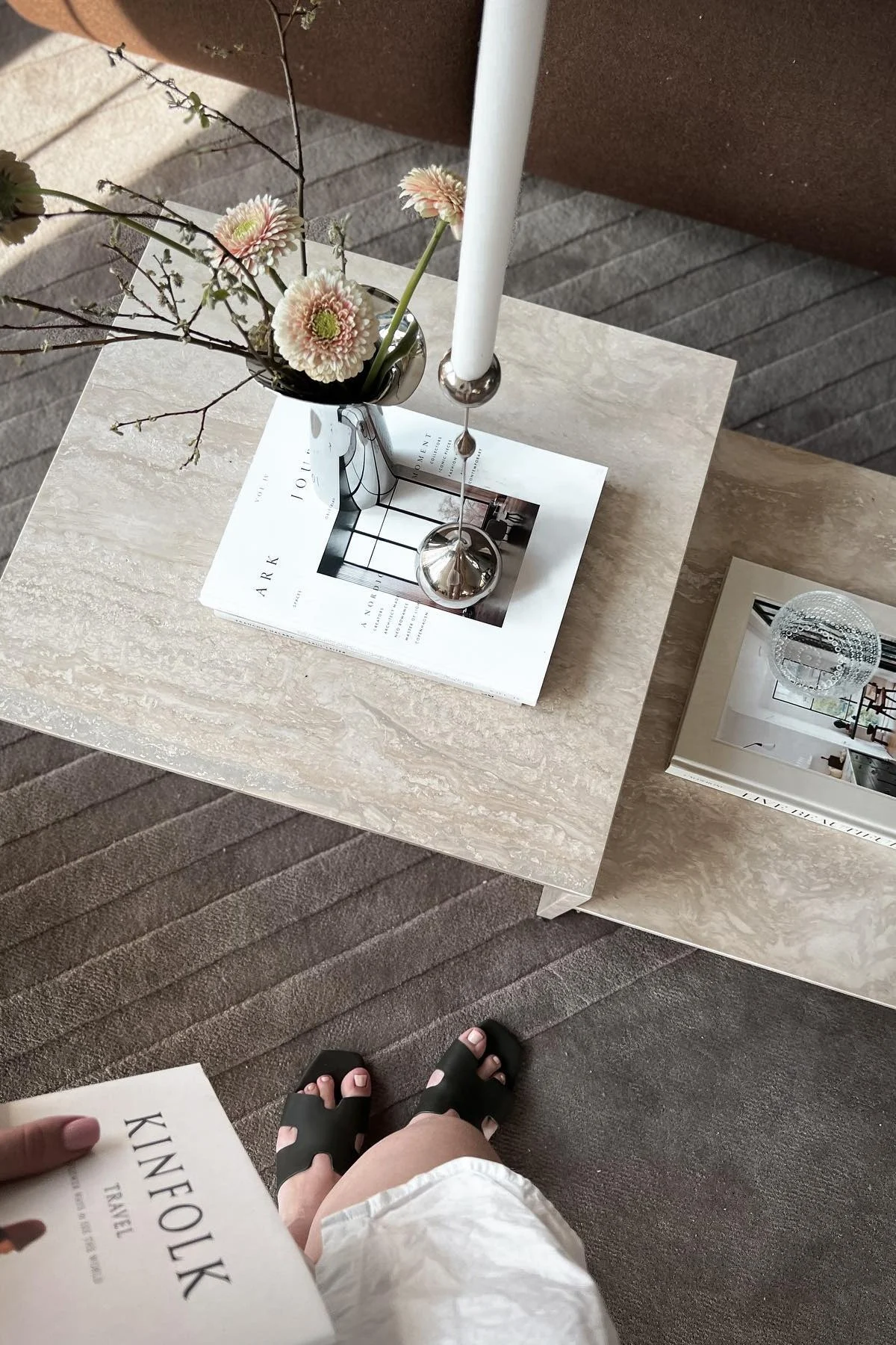 Der Distinct Beistelltisch von Ferm Living ist dekoriert mit einem Buch, dem Tender Kerzenhalter von Klong und der Bloom Botanica Vase mit frischen Blumen.