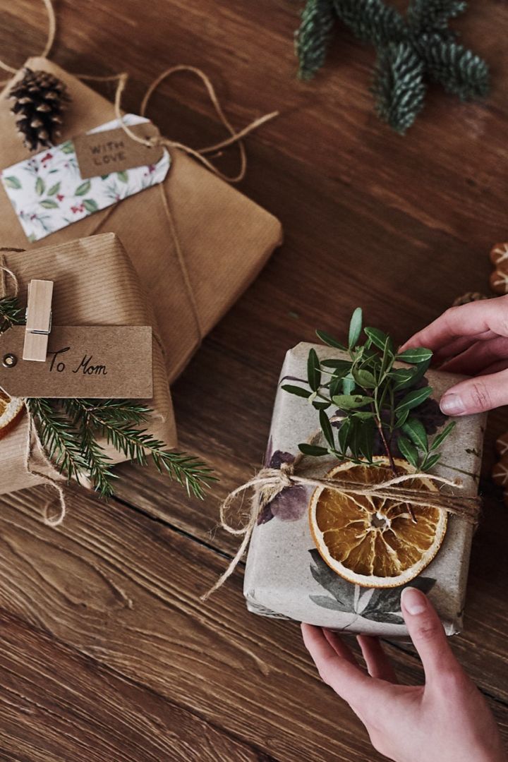 In Tapete verpackte Weihnachtsgeschenke, verziert mit getrockneten Orangenscheiben und Tannenzweigen.