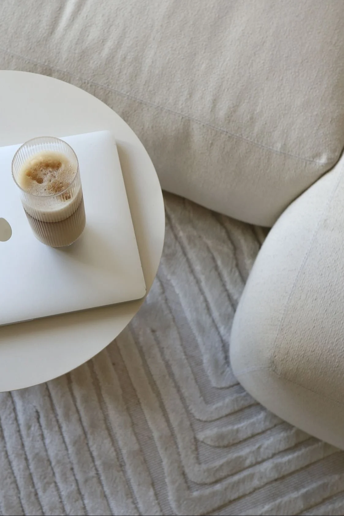 Hier sehen Sie einen perfekt zubereiteten Latte Macchiato in einem Longdrink-Glas aus der Ripple-Kollektion von Ferm Living, welches auf einem Couchtisch neben einer beigefarbenen Couch im Zuhause vom @ellesklingen steht.