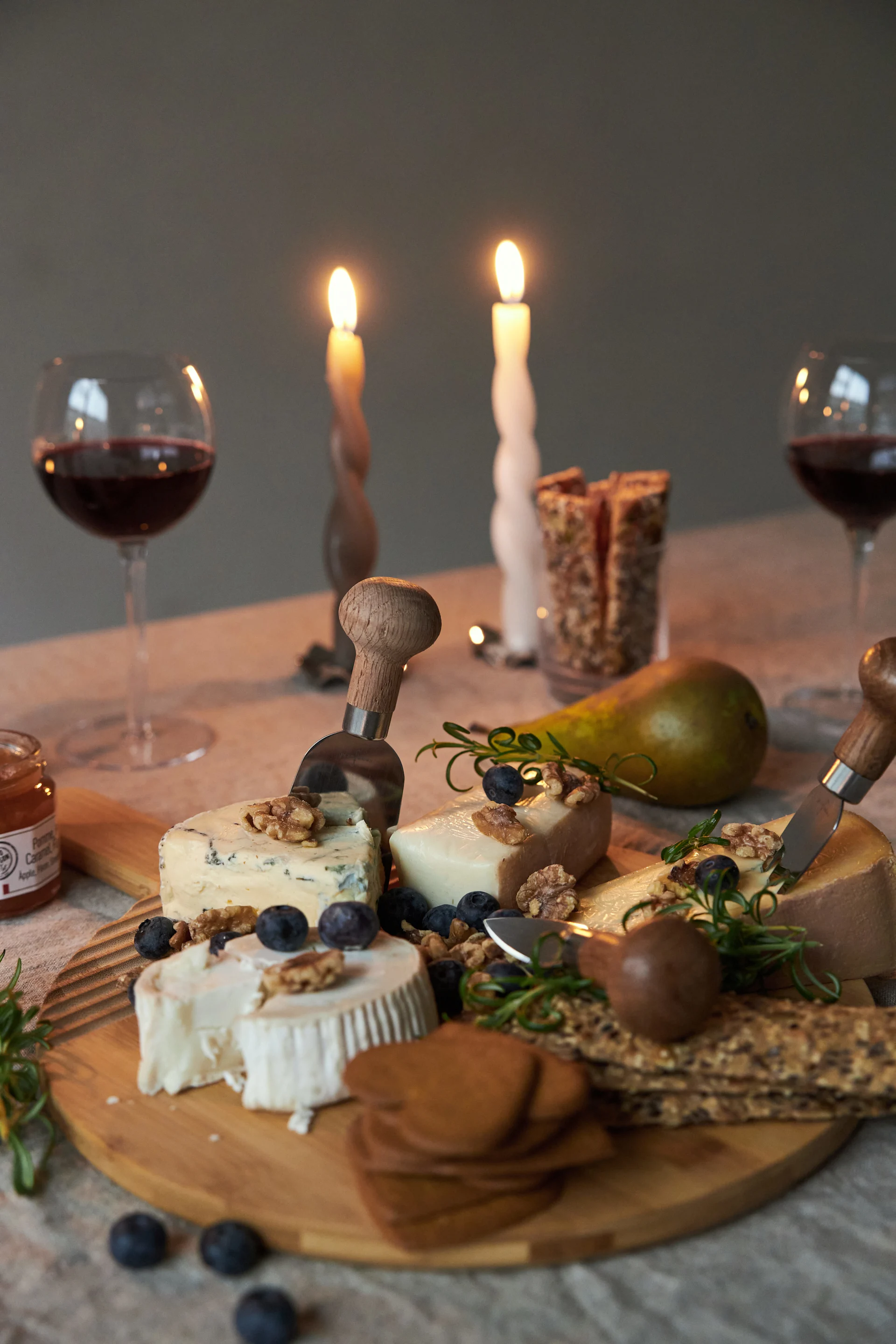 Ein Schneidebrett von Sagaform mit verschiedenen Käsesorten steht auf einem gedeckten Tisch.