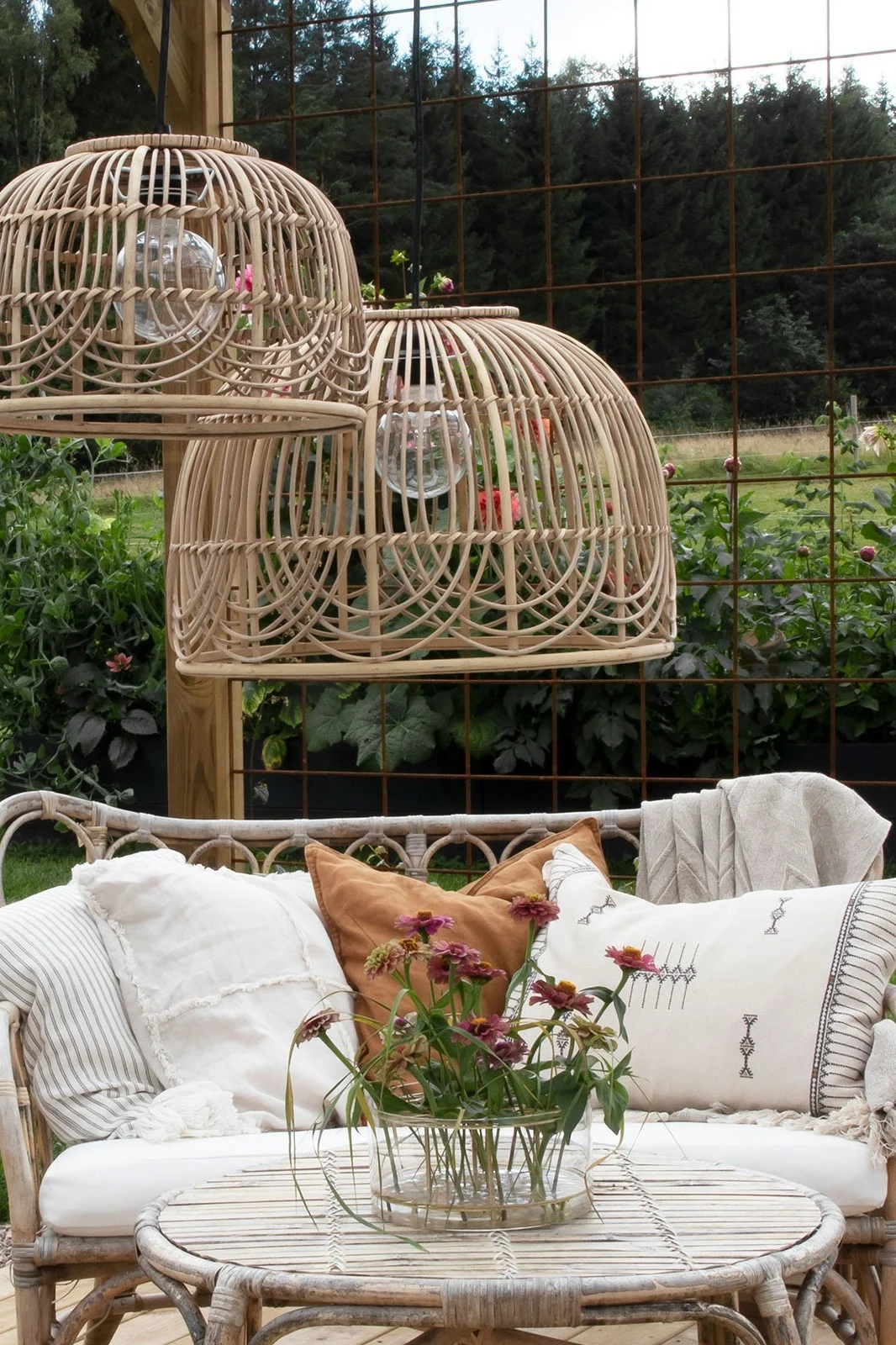 Der aus Rattan bestehende Lampenschirm Bali von Globen Lighting hängt auf einem Balkon, darunter stehen ein Rattan-Sofa und -Tisch und verleiht Ihrem Balkon den perfekten Boho-Look.