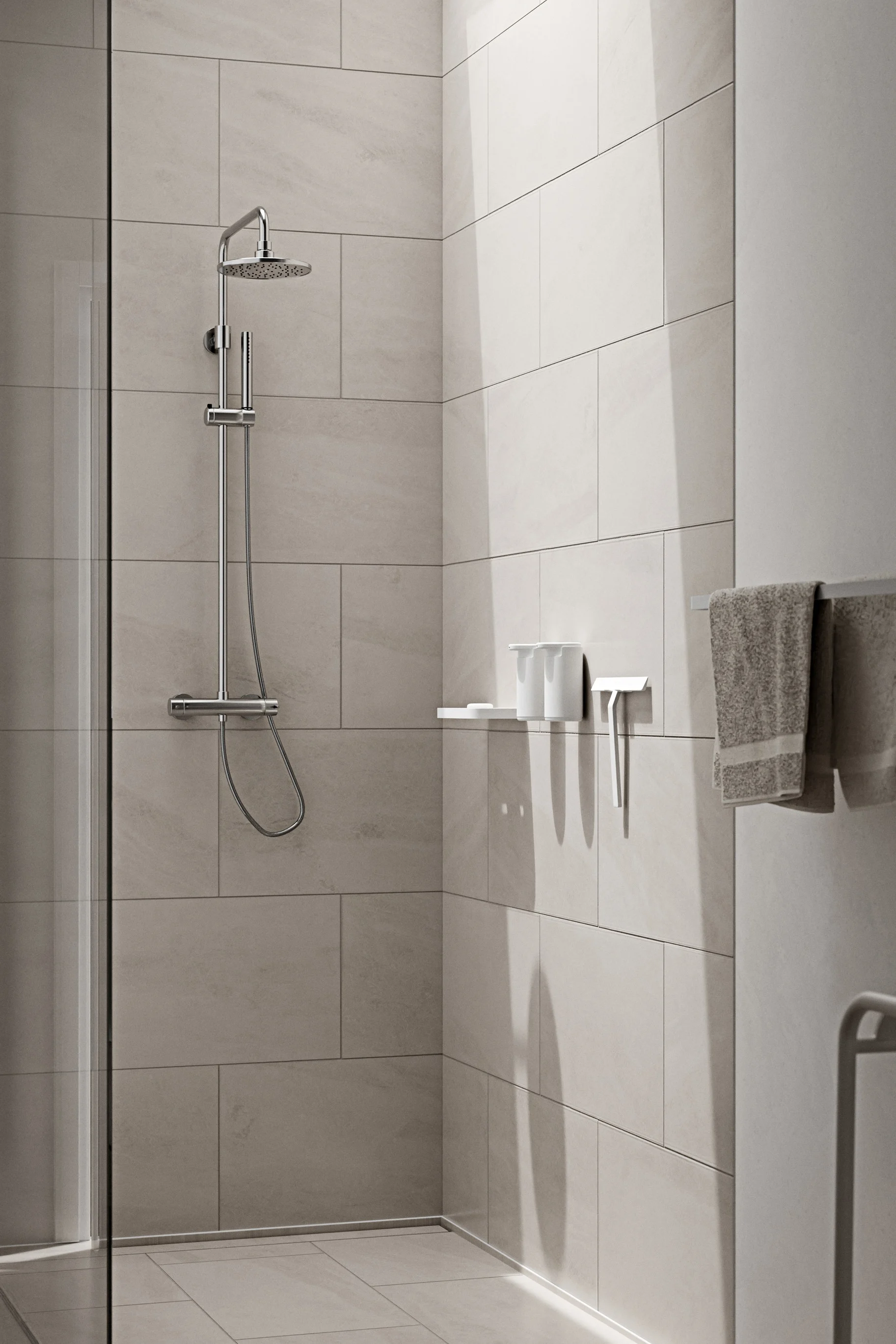 Eine moderne Dusche mit großen hellgrauen Fliesen, einem Chrom-Duschkopf, einem Regal mit weißen Toilettenartikeln und einem grauen Handtuch.