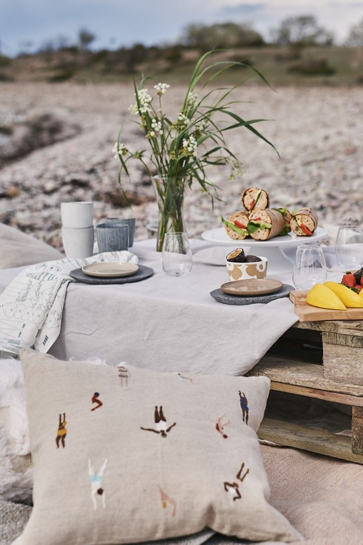 Ein luxuriöses Picknick am Strand auf Paletten, mit Kissen und einfachem Picknick-Essen. 