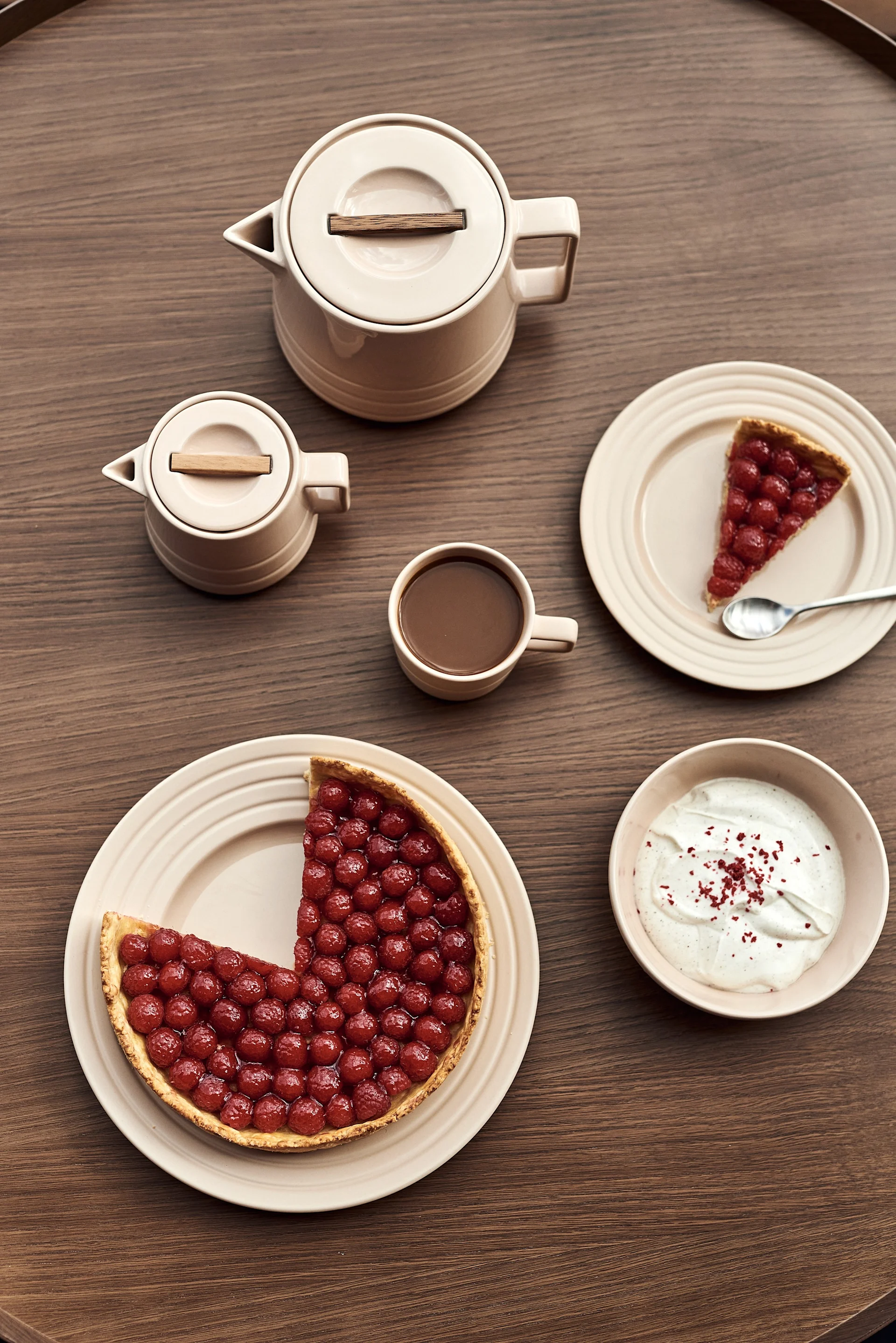 Wie wäre es mit einem neuen Geschirr-Service als Muttertagsgeschenk? Hier sehen Sie beigefarbene Teller in verschiedenen Größen mit Kuchen, eine Tasse, eine Teekanne, eine Schale und ein Milchkännchen aus der Lines-Kollektion von NJRD.