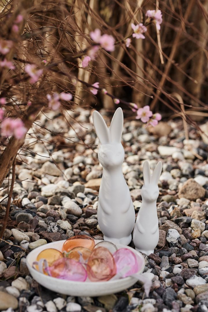 Osterdekorationen von DBKD in Form von Osterhasen und Eiern in verschiedenen Farben von Iittala stehen im Garten als Teil einer laufenden Ostereiersuche.
