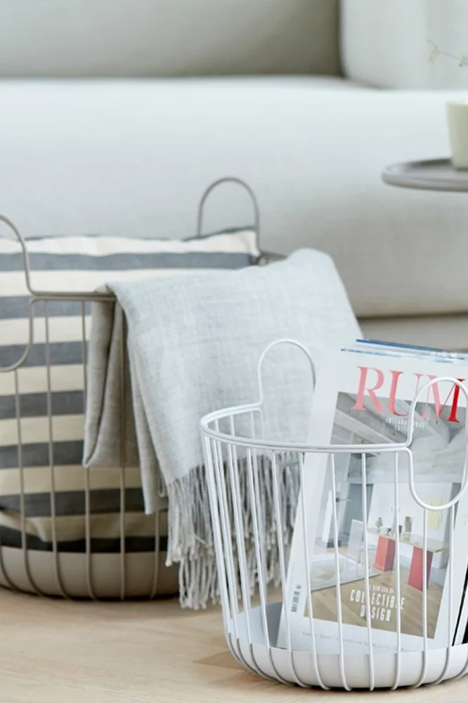 Aufräumen: Zwei Körbe von Zone Denmark mit Zeitschriften und Decken vor einer Couch.