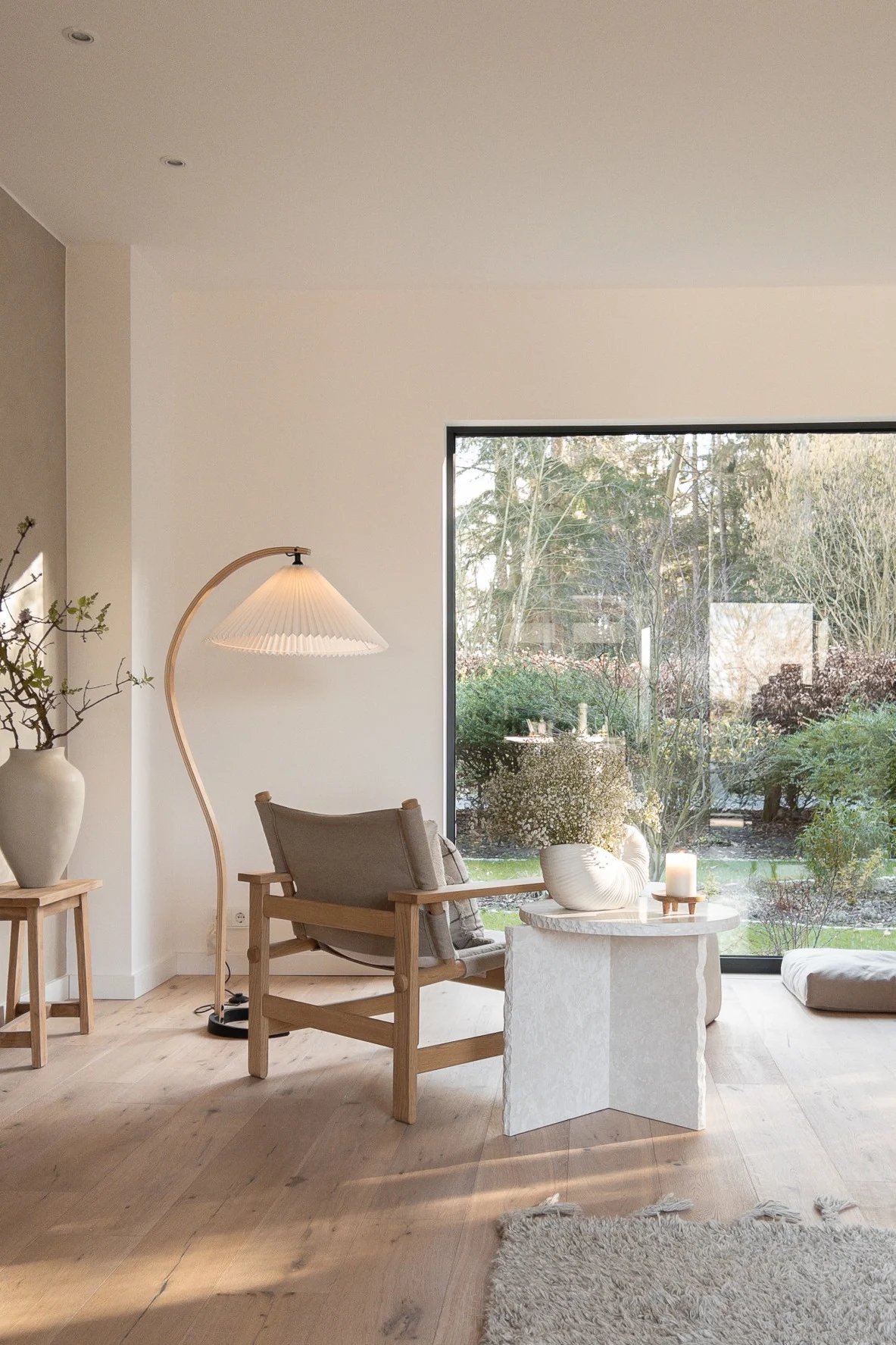 Das beigefarbene Wohnzimmer von haus_tannenkamp mit der Timberline Stehleuchte von Gubi, einem beigefarbenen Sessel und dem Mineral Sculptural Beistelltisch von Ferm Living.