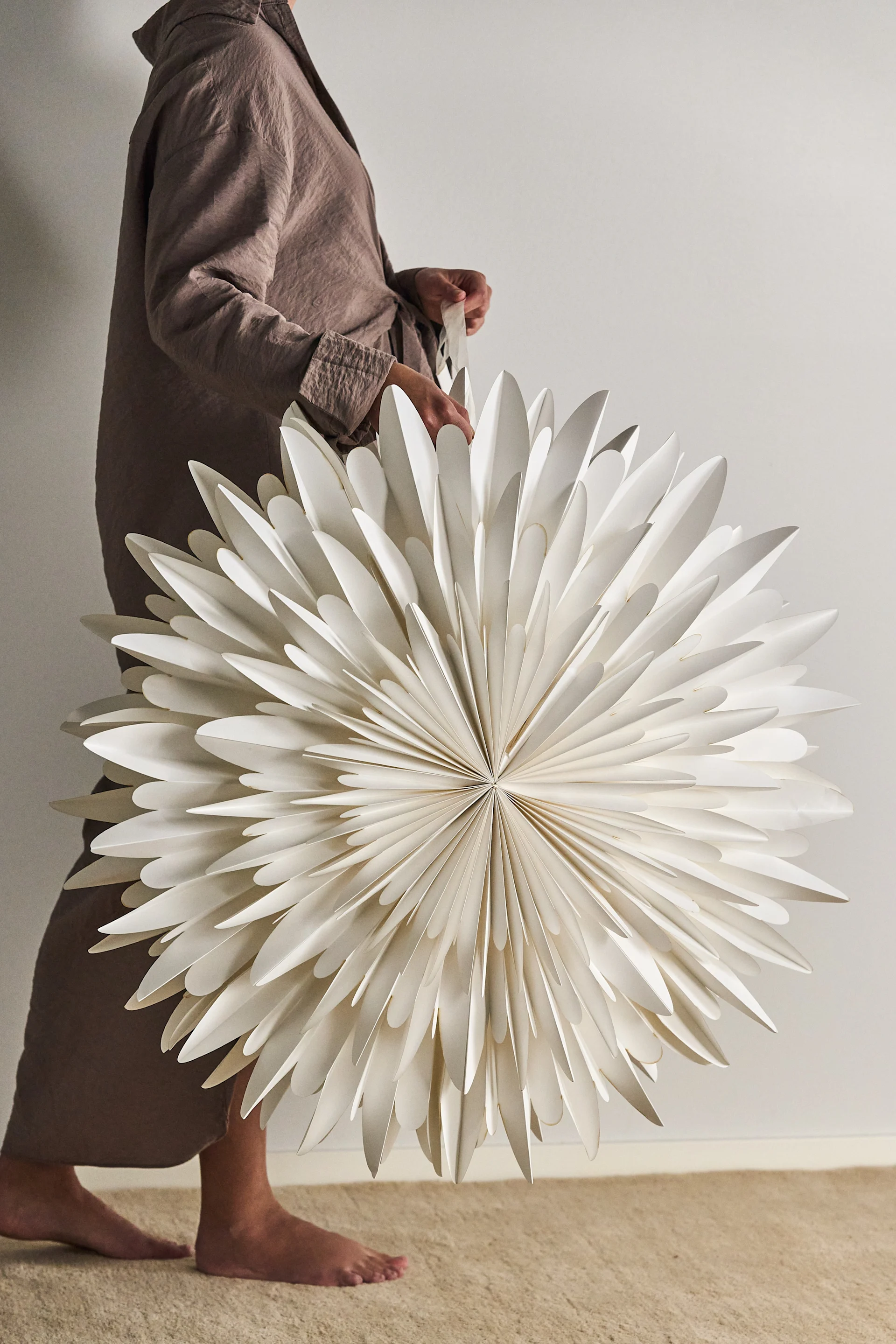 Eine Frau hält einen großen skandinavischen Weihnachtsstern in der Hand.