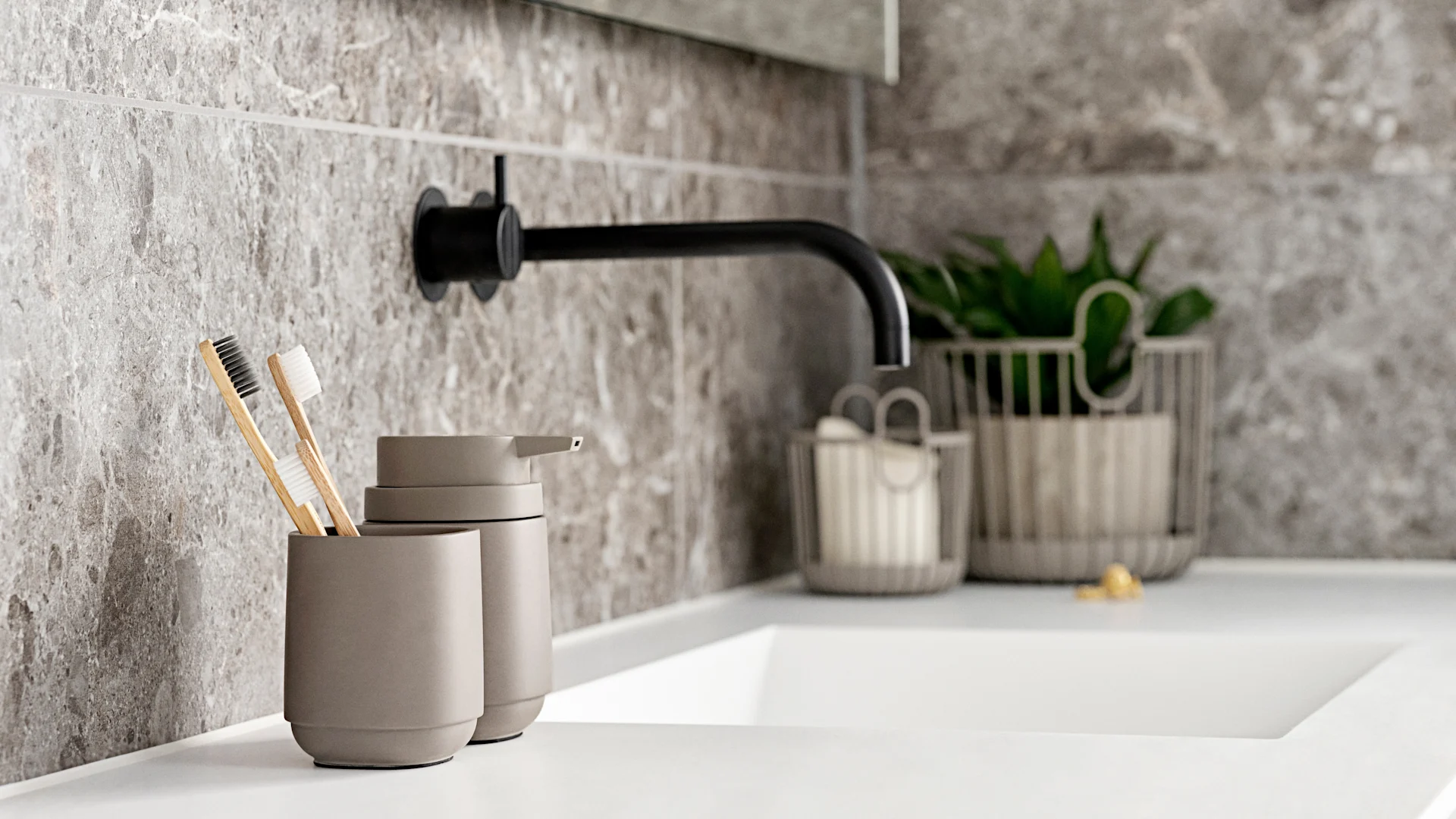 Modernes Badezimmer mit grauer Fliesenwand, weißem Waschbecken, schwarzem Wasserhahn, Seifenspender und Holzzahnbürsten.