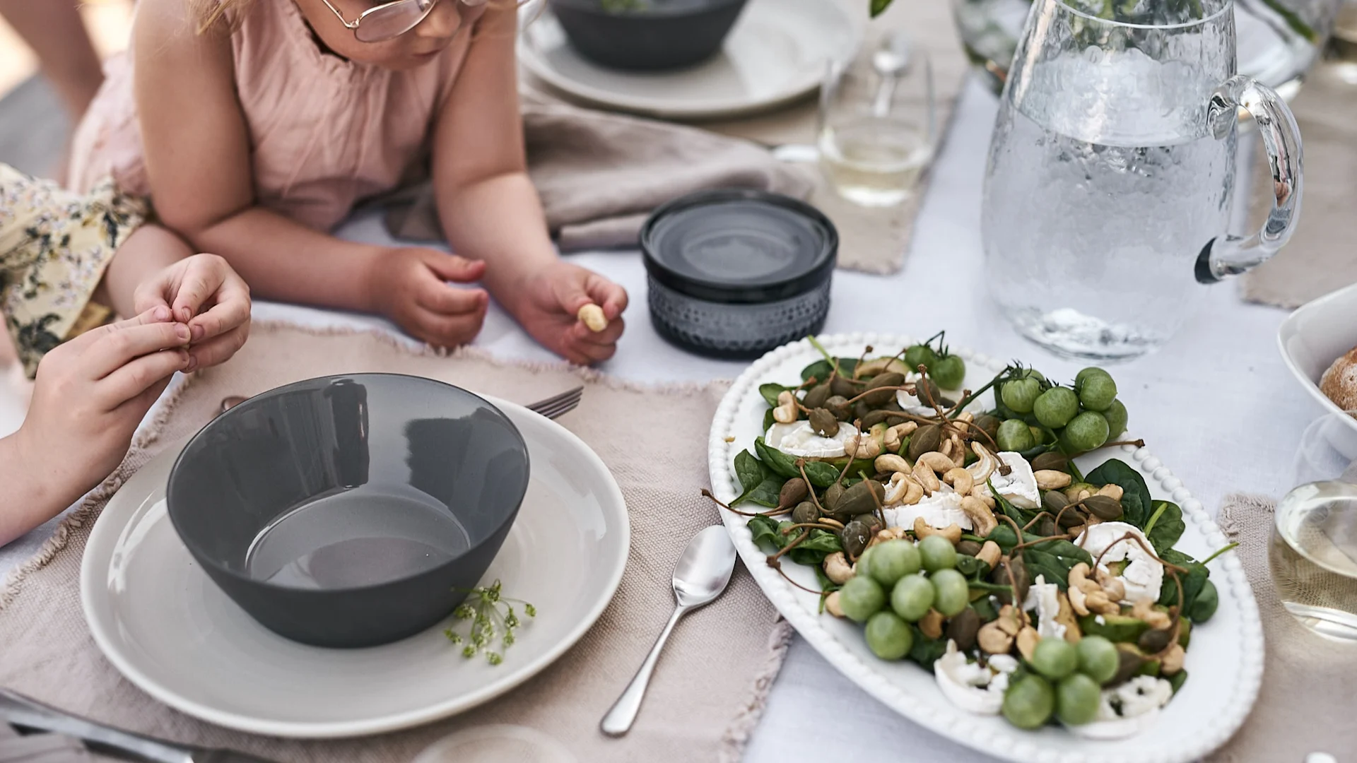 Kleine Finger greifen nach den Nüssen im frischen Sommersalat mit Ziegenkäse.