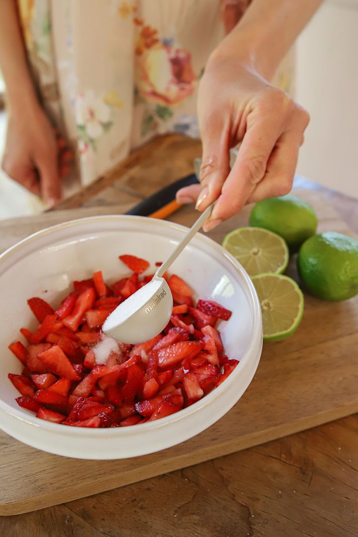 Klassische schwedische Erdbeertorte: Zur Vorbereitung gibt Frida die frisch geschnittenen Erdbeeren in eine Schüssel, bestreut sie mit Zucker und gibt Limettensaft darüber.