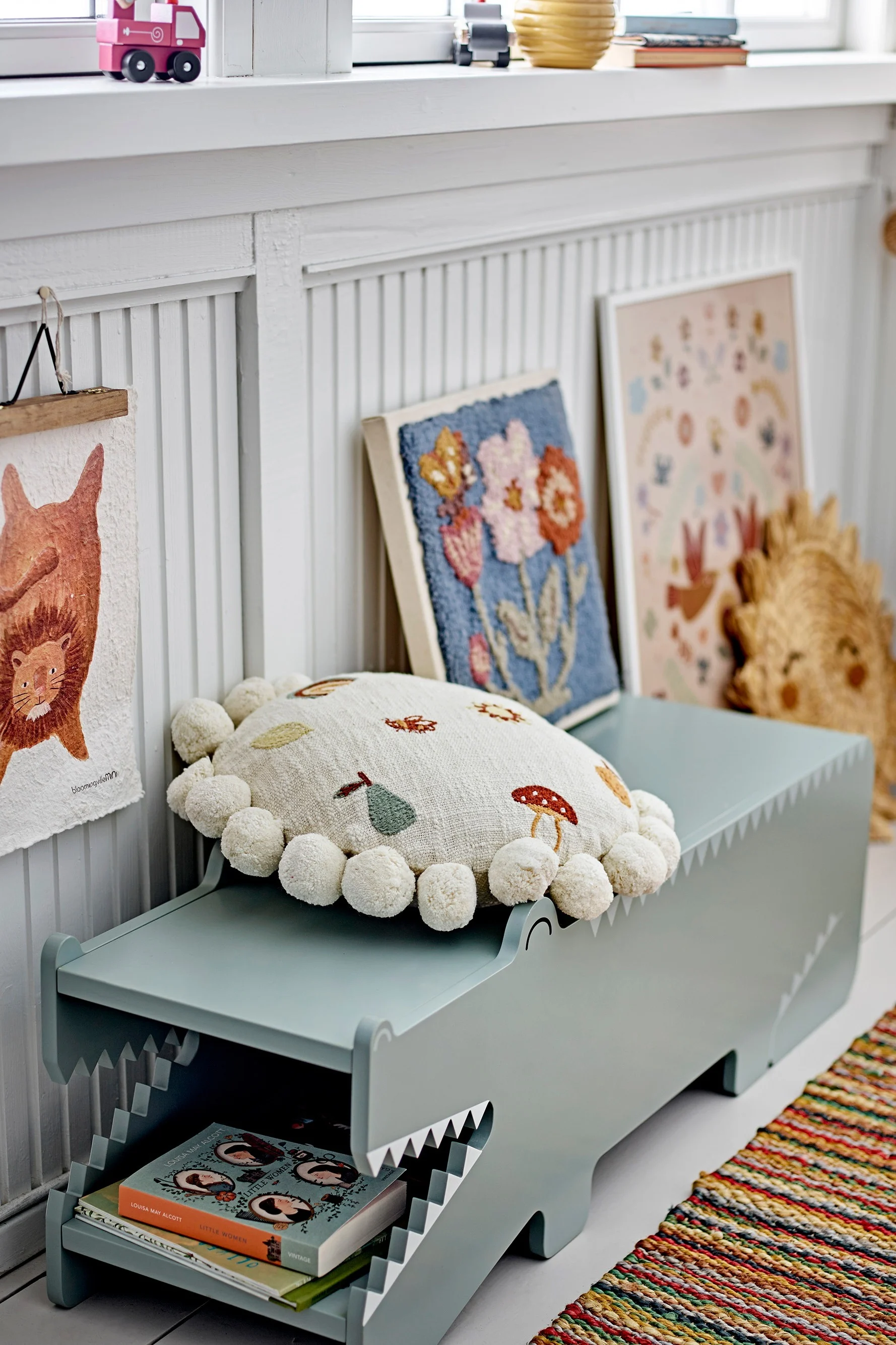 Aufräumen: Die Arnie Bank in Form eines Krokodils von Bloomingville steht in einem Kinderzimmer, umgeben von Büchern und Kissen.