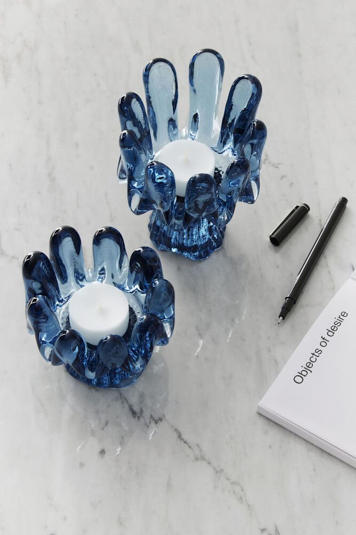 Wohntrends 2025: Zwei blaue Kerzenhalter aus der Solros-Kollektion von Kosta Boda stehen auf einem hellen Tisch.